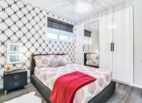 A fun and functional guest bedroom in the basement, with geometric wallpaper and red accents