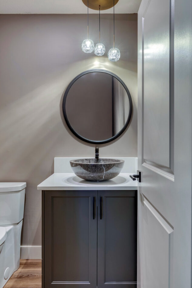 Powder room with round mirror and pendant light