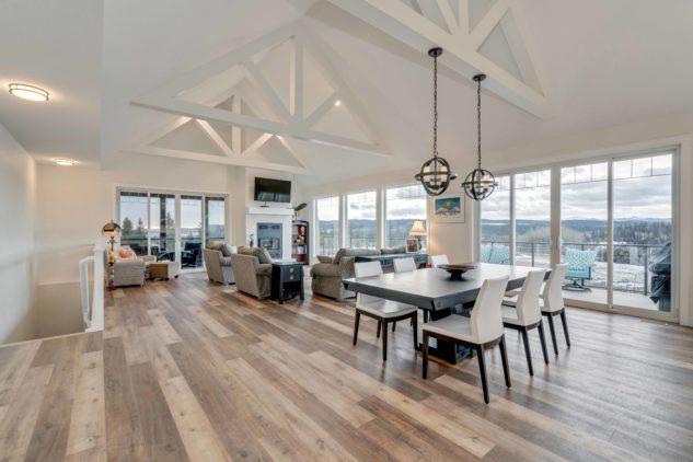 Open-concept living and dining area with vaulted ceilings and floor to ceiling height windows.