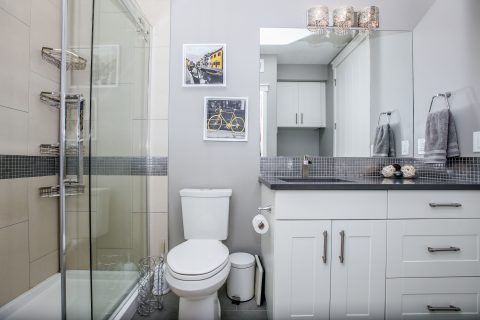 White bathroom with tiled shower and white cabinets in basement development 