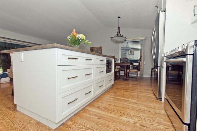 Custom white kitchen island with large amount of kitchen drawers and microwave