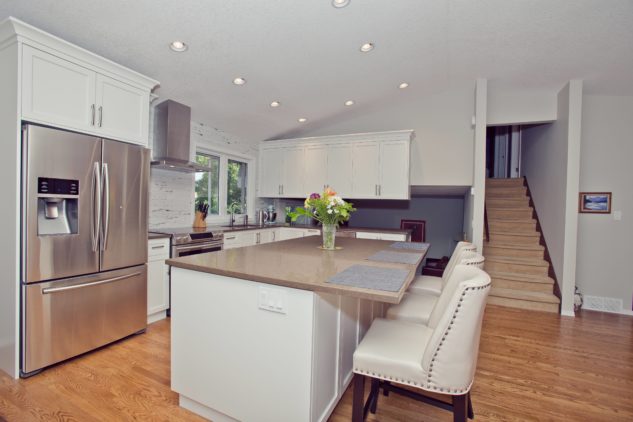 Large kitchen island with white cabinets, grey quartz countertops, vaulted ceilings