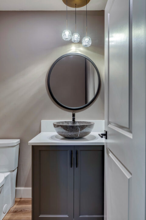Powder room with round mirror and pendant light
