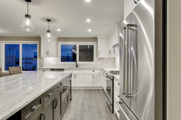Open-concept kitchen with large kitchen island. White cabinets with maple stained island.