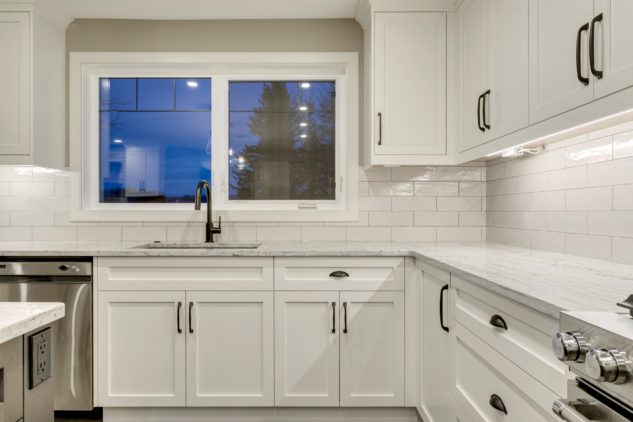Open-concept kitchen with large kitchen island. White cabinets with maple stained island.