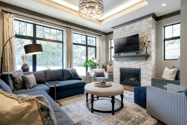 Living room with stone fireplace, custom mantle, tray ceiling and large windows