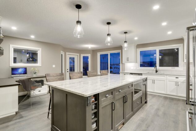 Open-concept kitchen with large kitchen island. White cabinets with maple stained island.