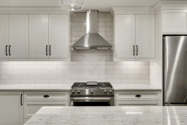 Open-concept kitchen with large kitchen island. White cabinets with maple stained island.