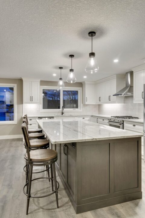 Open-concept kitchen with large kitchen island. White cabinets with maple stained island.