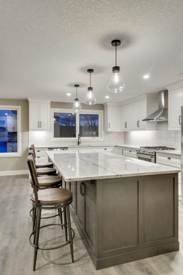 Open-concept kitchen with large kitchen island. White cabinets with maple stained island.
