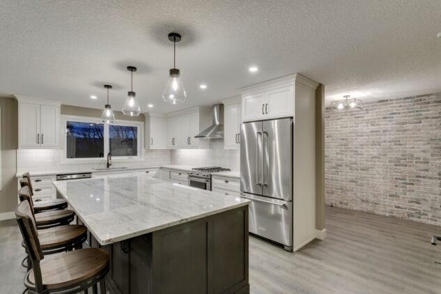 Open-concept kitchen with large kitchen island. White cabinets with maple stained island.