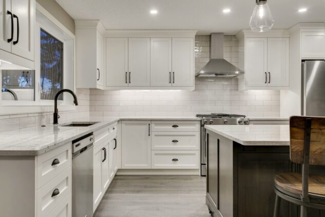 Open-concept kitchen with large kitchen island. White cabinets with maple stained island.