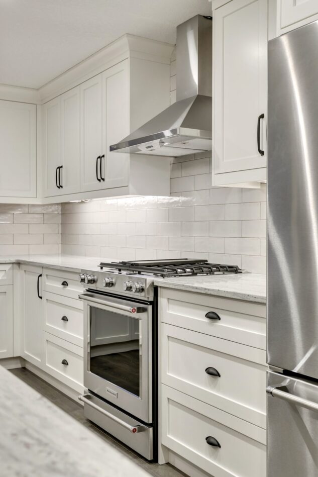Open-concept kitchen with large kitchen island. White cabinets with maple stained island.