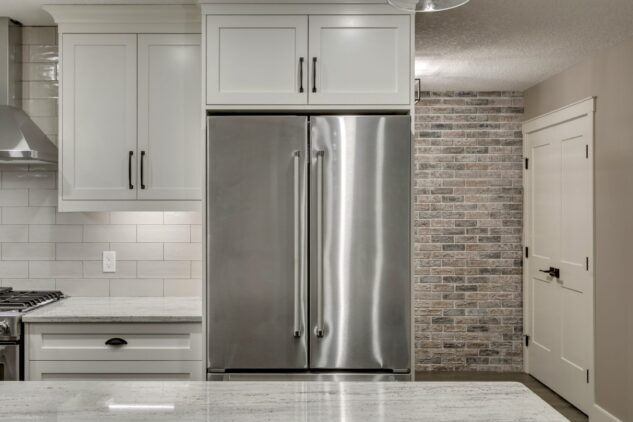 Open-concept kitchen with large kitchen island. White cabinets with maple stained island.