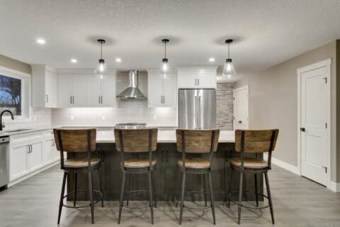 Open-concept kitchen with large kitchen island. White cabinets with maple stained island.