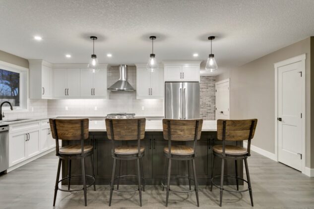 Open-concept kitchen with large kitchen island. White cabinets with maple stained island.