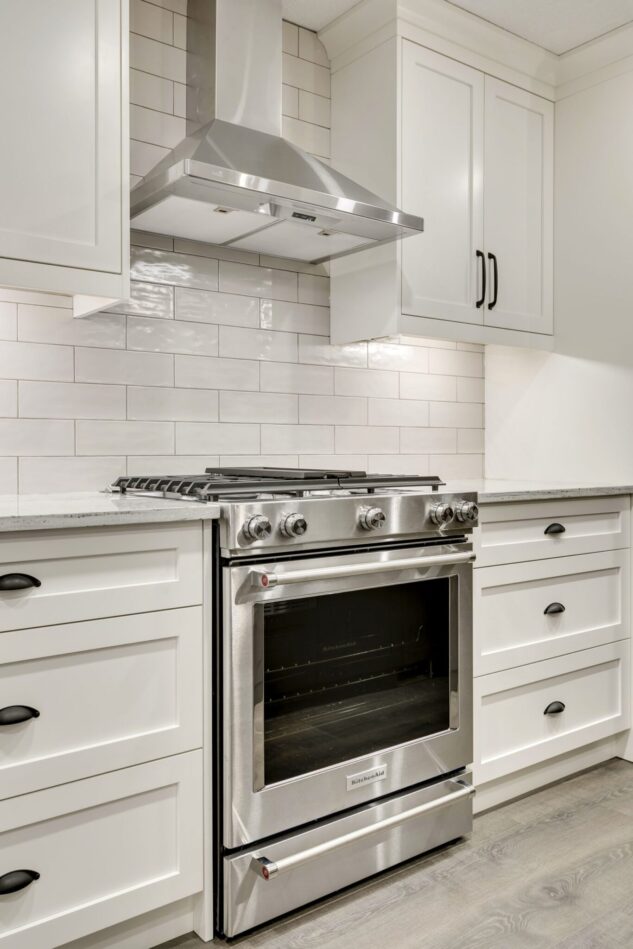 Open-concept kitchen with large kitchen island. White cabinets with maple stained island.