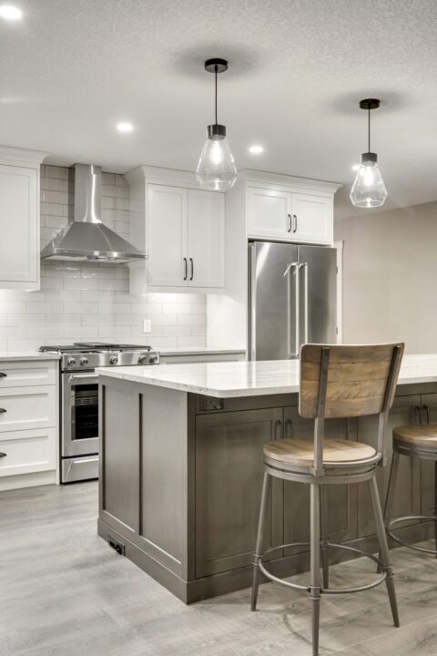 Open-concept kitchen with large kitchen island. White cabinets with maple stained island.