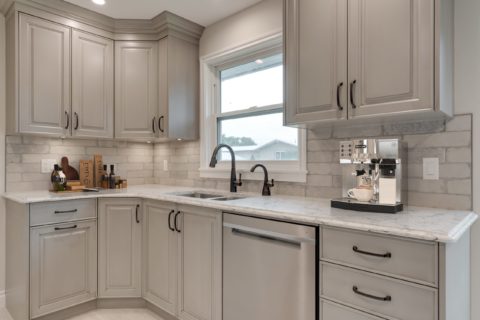 Grey kitchen cabinets with a tiled backsplash and LVP flooring