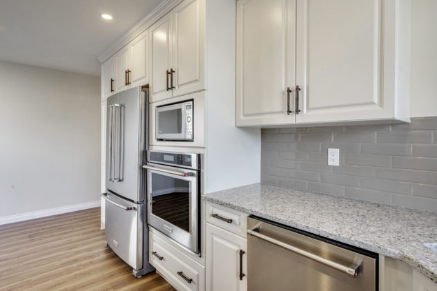 Custom white cabinetry with wall oven and quartz countertops. Stainless steel appliances. 