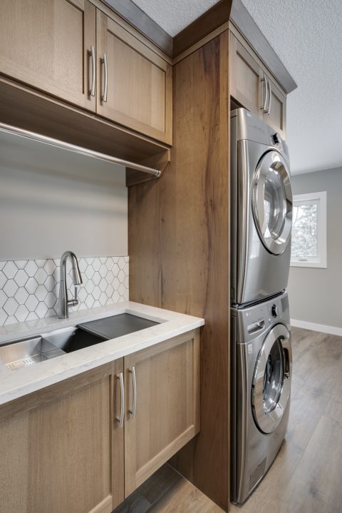 Laundry Room with custom cabinetry and tiled backsplash 