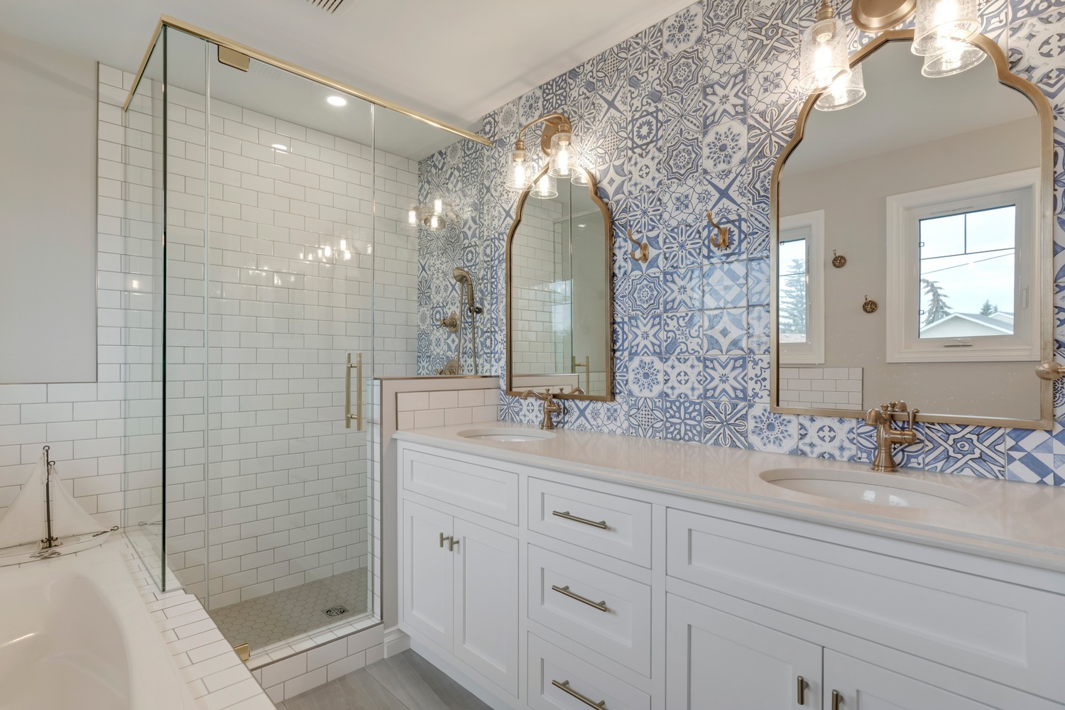 Ensuite with white Shaker cabinets, stone countertops, patterned blue and white tile and gold fixtures