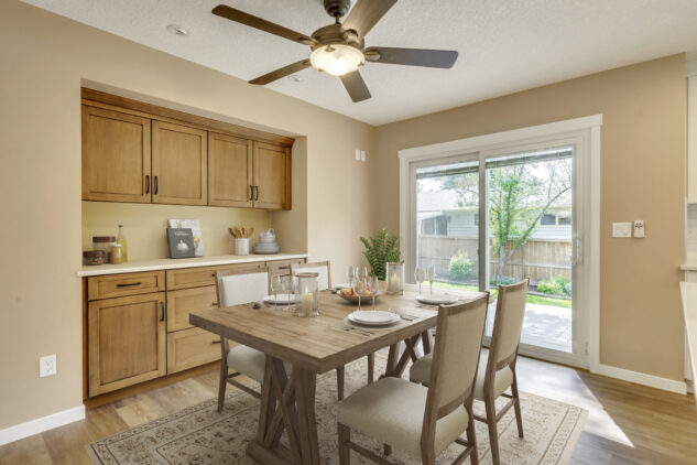 Stained custom dining hutch with farmhouse style dining table. Ceiling fan above.
