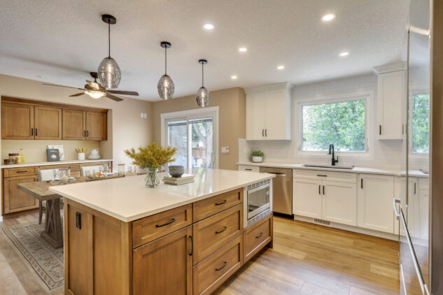 Stained kitchen island with white perimeter cabinetry. Stained custom dining hutch with farmhouse style dining table.