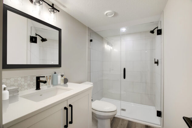 Ensuite with white cabinetry and tiled shower. Black handles and bath accessories