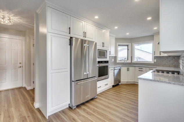 Custom white cabinetry with wall oven and quartz countertops. Stainless steel appliances. 