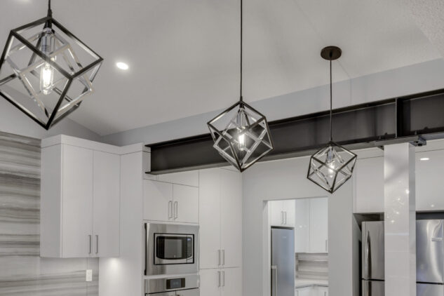 Modern high gloss kitchen cabinetry with grey quartz countertops and exposed steel beam