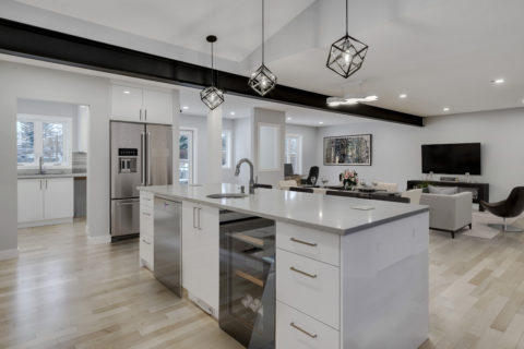 Modern high gloss kitchen cabinetry with grey quartz countertops over looking the dining and living room