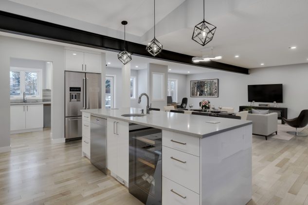 Modern high gloss kitchen cabinetry with grey quartz countertops over looking the dining and living room