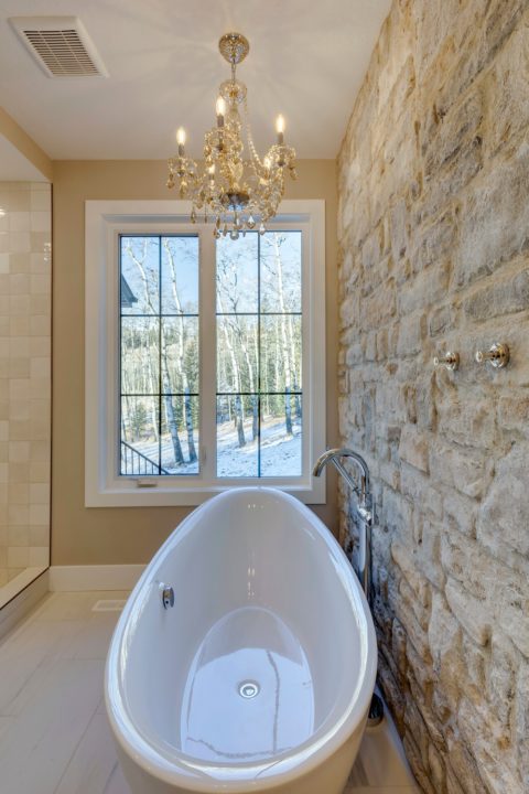 Ensuite free-standing tub with custom stone wall