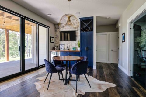 Basement bar with blue cabinetry and stone wall