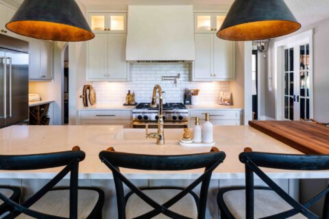 Venetian plaster hood fan with custom white cabinetry and large island with quartz countertops
