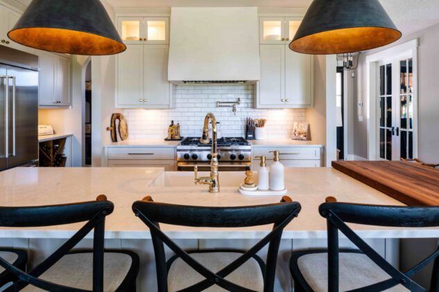 Venetian plaster hood fan with custom white cabinetry and large island with quartz countertops