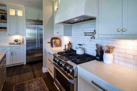 Kitchen gas cooktop with custom white cabinetry and quartz countertops