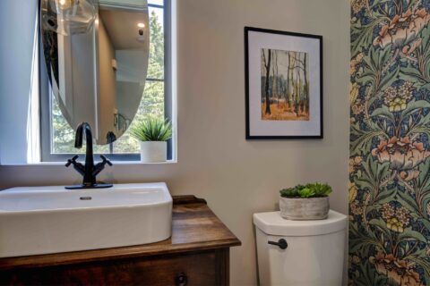 Powder room with floating oval mirror and custom furniture piece vanity