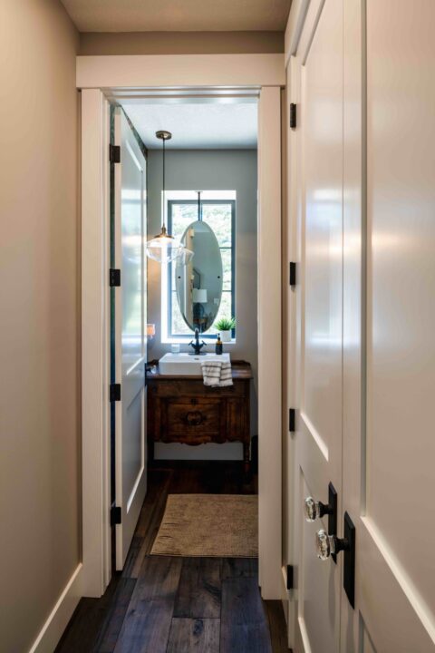 Powder room with floating oval mirror and custom furniture piece vanity