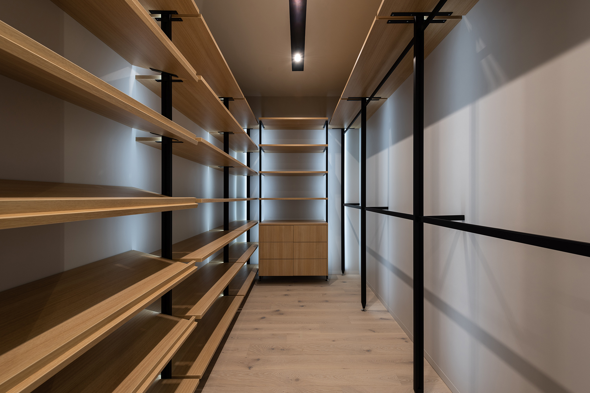 Walk-in closet with open wooden shelving and metal rods.