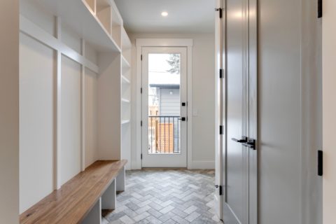 Mudroom with herringbone tiled floors and walnut benchtop. Calgary, Alberta custom home builder.