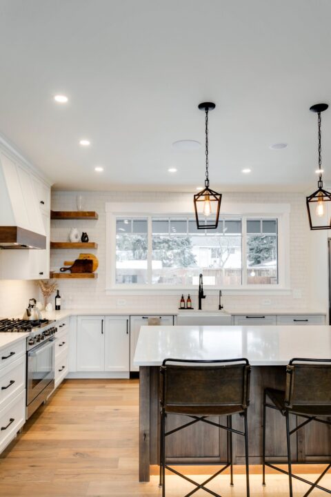 Calgary infill custom home builder. White paint-grade kitchen with knotty maple island. Floating shelves, pendant lights, full height subway tile backsplash.  Modern farmhouse.