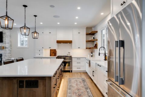 Calgary infill custom home builder. White paint-grade kitchen with knotty maple island. Floating shelves, pendant lights, full height subway tile backsplash.  