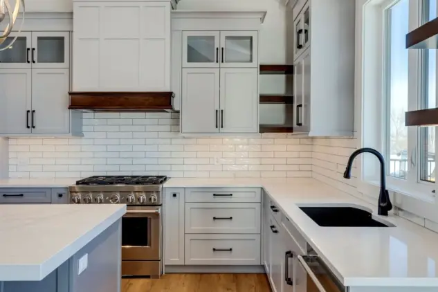 Closeup of custom hood fan and Shaker cabinetry with glass front accent cabinet doors and open shelving