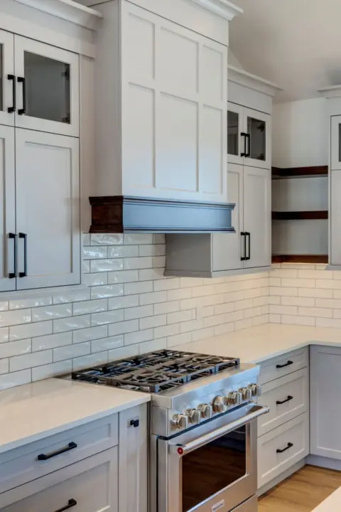 Close up of custom Shaker cabinetry, hood fan, and open shelving in custom Dewinton home