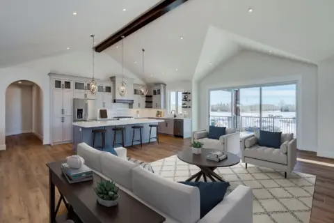 Kitchen and great room of custom Dewinton home featuring soaring vaulted ceiling and wood beam accent