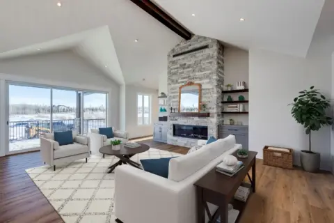 Light-filled great room with vaulted ceilings, accent beam, floor-to-ceiling stone fireplace