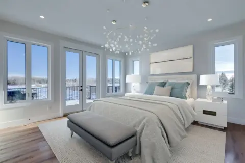 Large primary bedroom of custom Dewinton home with windows on two walls and French doors