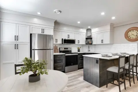 Kitchen and dining space in legal Calgary basement suite featuring large window, two-tone custom cabinetry, pantry, and eating bar.
